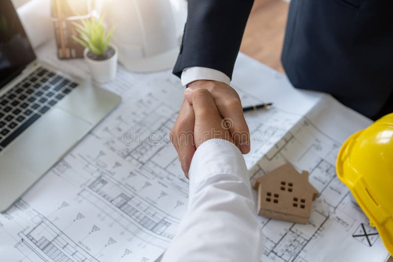 Handshake of engineer with finance investor as meeting and looking at project on blue print stock images Handshake of engineer with finance investor as meeting and looking at project on blue print stock images