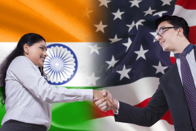 Indian businesswoman shaking hands with American businessman in front of Indian and American flags. Indian businesswoman shaking hands with American businessman in front of Indian and American flags