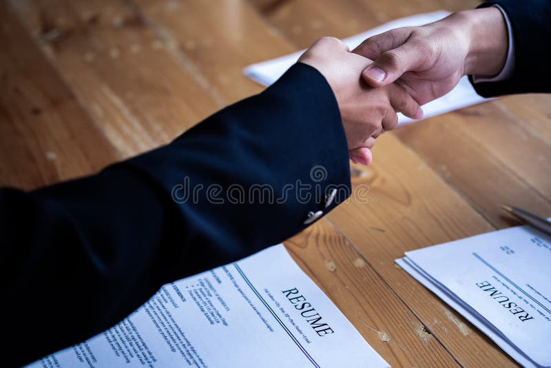 Handshake success job interviewing. Job applicant having interview. Shaking Hand With Resume On Desk. Employer giving an handshake stock photos