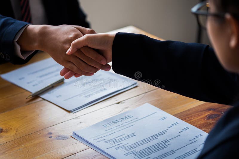 Handshake success job interviewing. Job applicant having interview. Shaking Hand With Resume On Desk. Employer giving an handshake royalty free stock photography