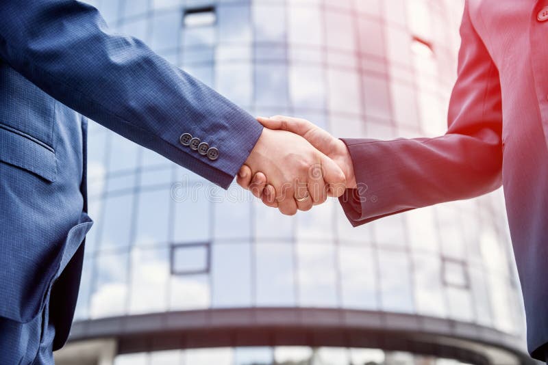 Handshakes against new business center close up