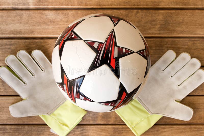 Handskar för fotbollboll och goaliepå träbakgrund arkivfoto Handskar för fotbollboll och goaliepå träbakgrund arkivfoto