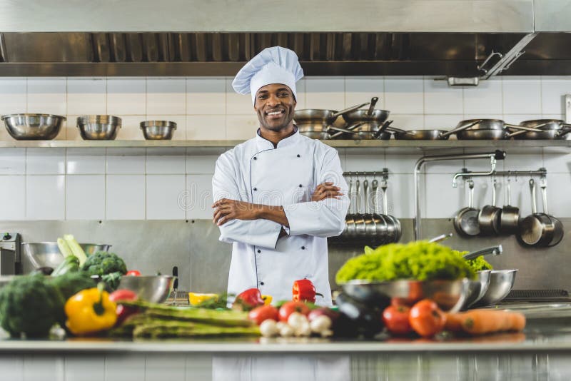 Handsome african american chef standing at restaurant kitchen with crossed arms and looking stock images Handsome african american chef standing at restaurant kitchen with crossed arms and looking stock images
