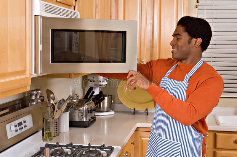 Bel Afro-Americano, l'uomo utilizza il forno a microonde per cucinare la cena in cucina.