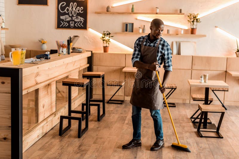 Handsome African American Worker Sweeping with Broom Stock Image