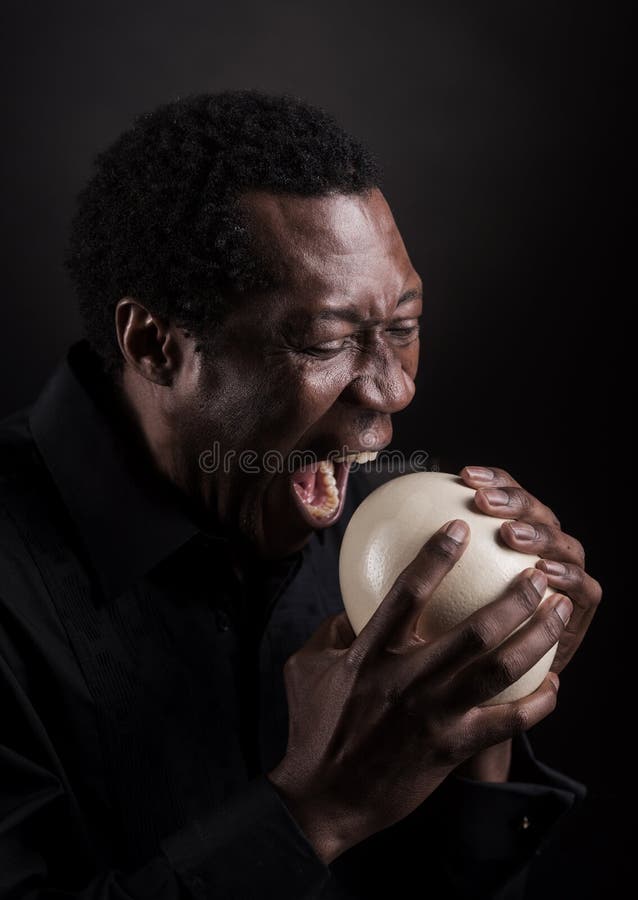 Handsome african black man eating ostrich egg. royalty free stock images