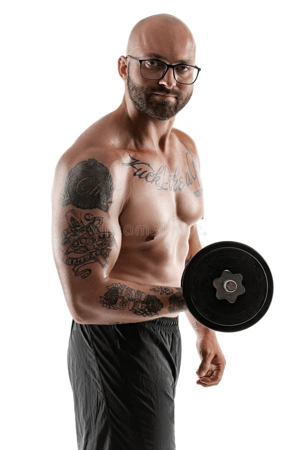 Athletic bald, tattooed man in black shorts is posing with a dumbbell isolated on white background. Close-up portrait. stock photos