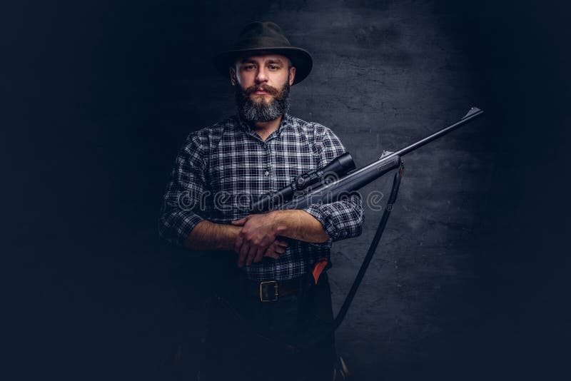 Handsome bearded hunter traveler in a fleece shirt and hat holds rifle with a sight. royalty free stock photos Handsome bearded hunter traveler in a fleece shirt and hat holds rifle with a sight. royalty free stock photos