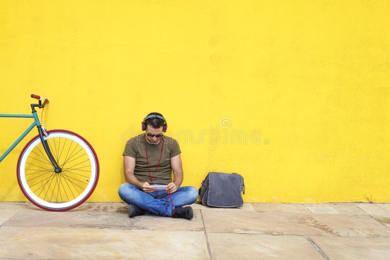 Handsome bearded man using a mobile phone while listening to music in headphones, spending time with pleasure while sitting near royalty free stock images Handsome bearded man using a mobile phone while listening to music in headphones, spending time with pleasure while sitting near royalty free stock images