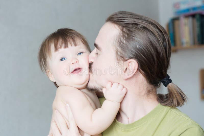 Handsome bearded young man kissing infant little girl. Happy smiling father and baby daughter portrait royalty free stock images Handsome bearded young man kissing infant little girl. Happy smiling father and baby daughter portrait royalty free stock images