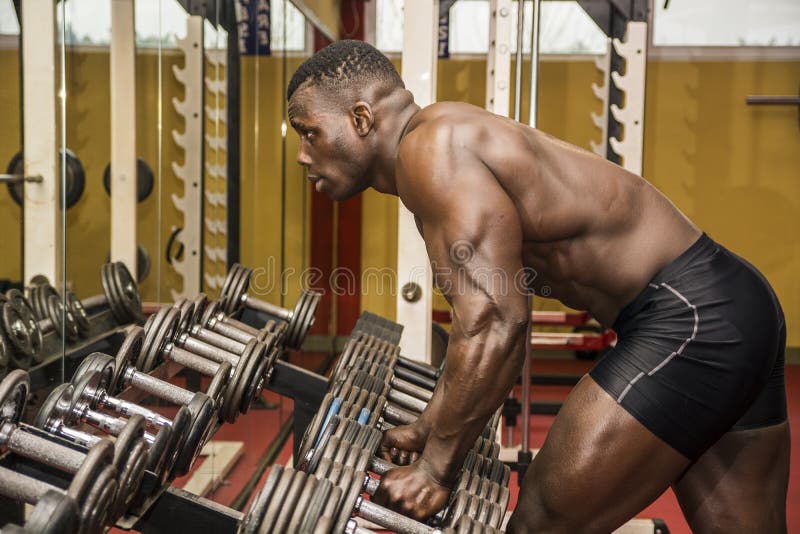 Handsome black male bodybuilder resting after workout in gym stock image