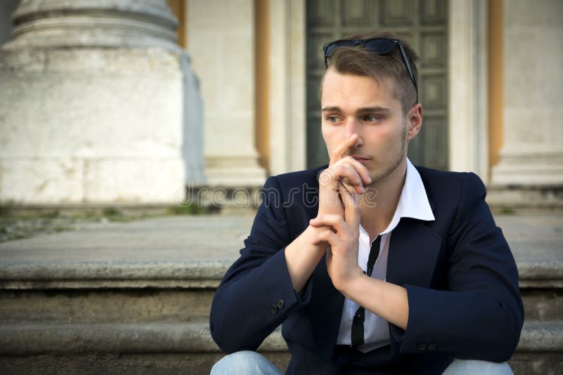 Handsome blond young man with marble columns behind him royalty free stock images