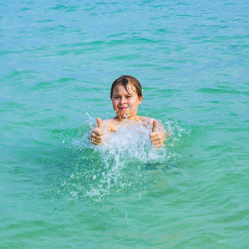 Handsome boy has fun in the ocean and shows thumbs up