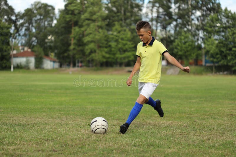 Handsome boy soccer player in a yellow t-shirt on a soccer field with a ball