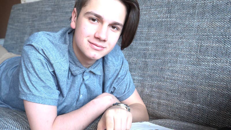 Handsome boy teenager talking on the phone sits on a gray sofa royalty free stock images Handsome boy teenager talking on the phone sits on a gray sofa royalty free stock images