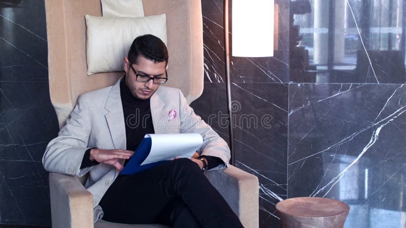 Handsome businessman in armchair checking up documents
