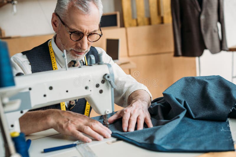 Handsome dressmaker sewing cloth with sewing machine royalty free stock photos