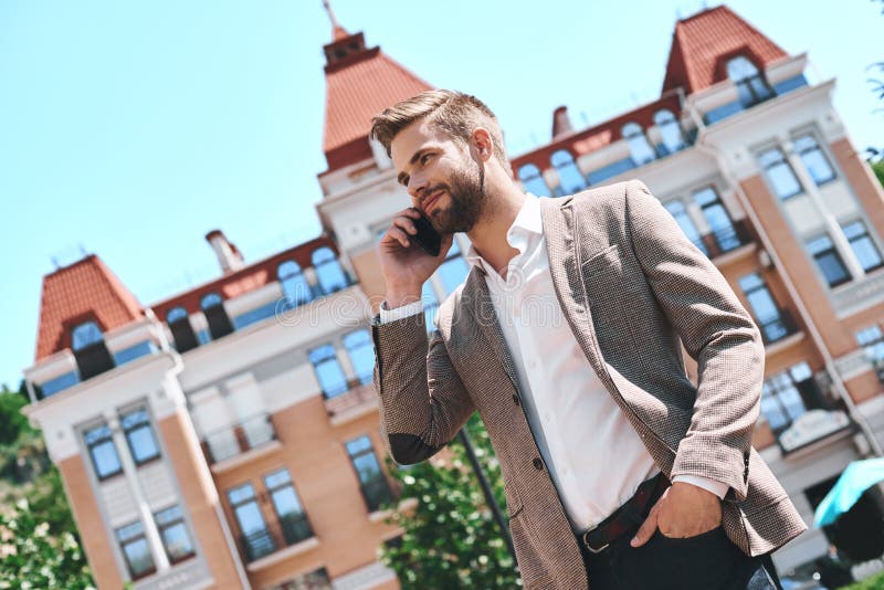 Handsome elegant young man in the city, talking on his cellphone while smiling stock photos Handsome elegant young man in the city, talking on his cellphone while smiling stock photos