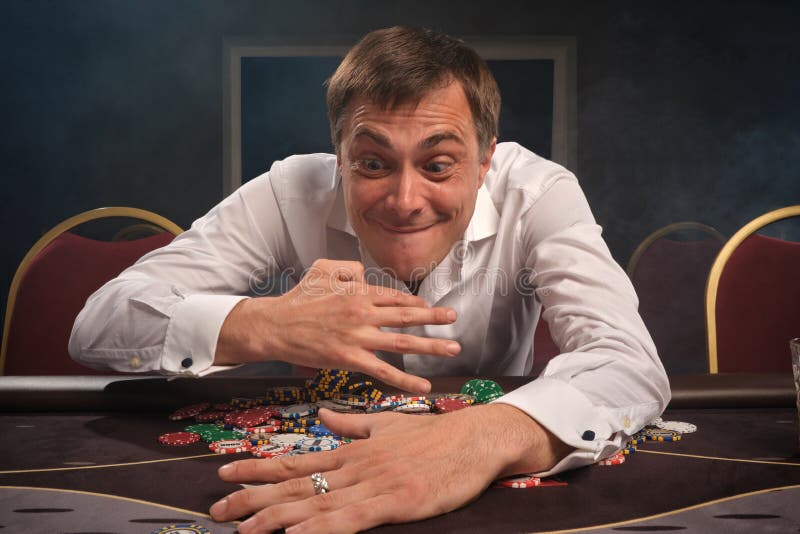 Handsome emotional man is playing poker sitting at the table in casino. royalty free stock photos Handsome emotional man is playing poker sitting at the table in casino. royalty free stock photos
