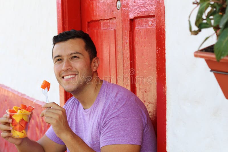 Handsome ethnic man eating a fruit bowl stock images