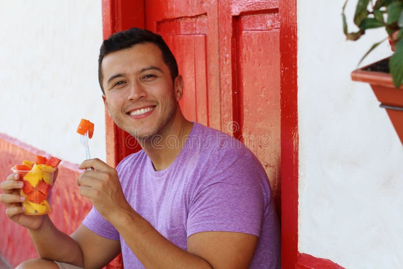 Handsome ethnic man eating a fruit bowl stock images