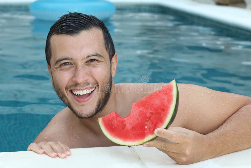 Handsome ethnic man eating watermelon in the pool stock photos