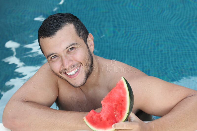 Handsome ethnic man eating watermelon in the pool stock photos