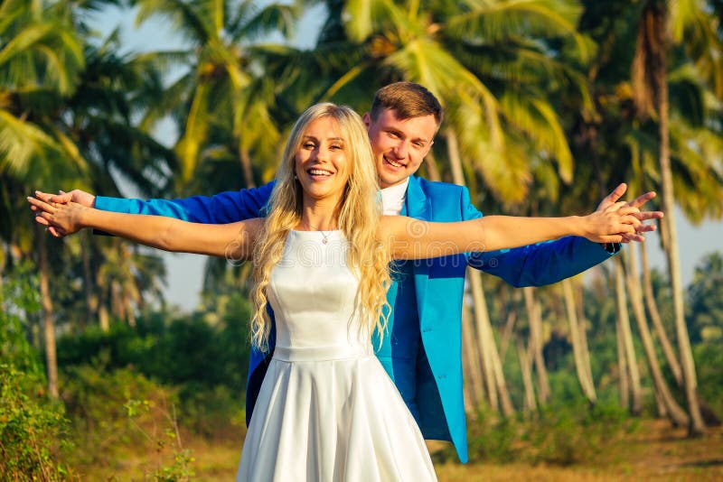 Handsome groom in a luxury suit and a beautiful bride in a beautiful wedding dress smiling and posing on a background of royalty free stock images Handsome groom in a luxury suit and a beautiful bride in a beautiful wedding dress smiling and posing on a background of royalty free stock images