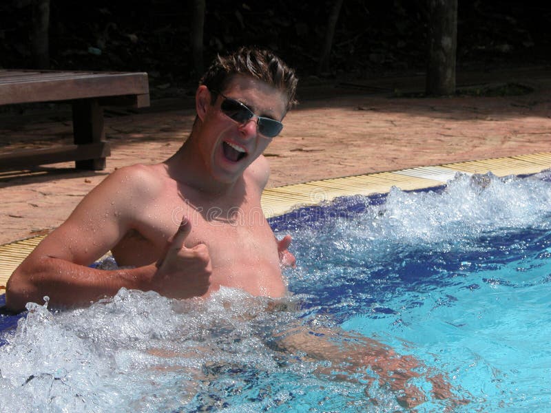 A handsome guy with glasses is sitting in the jacuzzi, raising his thumb up. Relax in the pool while on holiday in the stock photos A handsome guy with glasses is sitting in the jacuzzi, raising his thumb up. Relax in the pool while on holiday in the stock photos