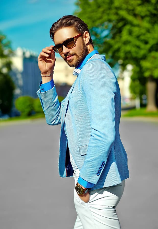 High fashion look.Young stylish confident happy handsome businessman model  man in blue suit cloth lifestyle in the street behind sky in sunglasses -  Stock Image - Everypixel