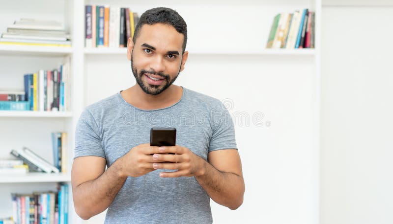 Handsome hispanic hipster man with beard sending message at mobile phone royalty free stock photo
