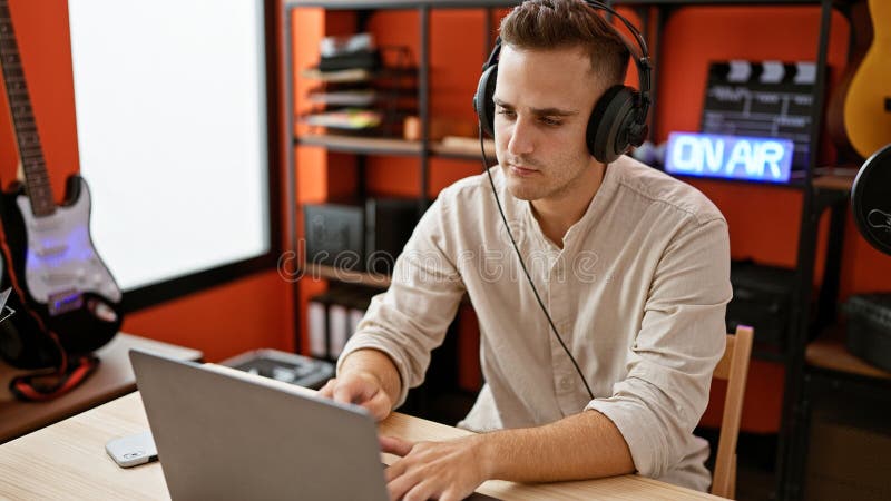 Handsome hispanic man with headphones working on laptop in music studio stock photos