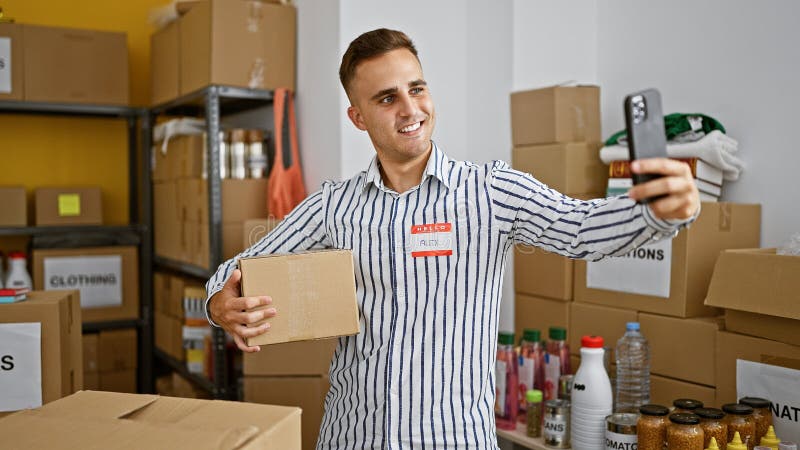Handsome hispanic man taking a selfie in a warehouse holding cardboard box stock photo