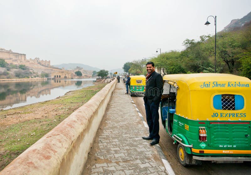 JAIPUR, INDIA: Handsome indian driver stand near the indian moto rickshaw & waiting for the passengers on the road. Jaipur, with populat. 6,664000, is capital of Rajasthan