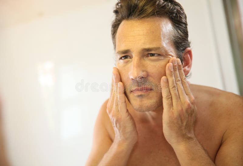 Middle-aged man in bathroom applying facial lotion. Problem wrinkle stock images, royalty-free photos and pictures