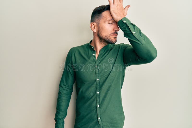 Handsome man with beard wearing casual clothes surprised with hand on head for mistake, remember error stock photo