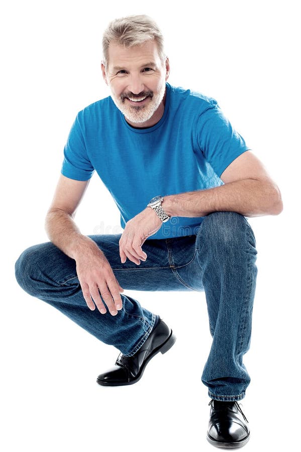 Smiling mature man sitting crouched and posing stock images.