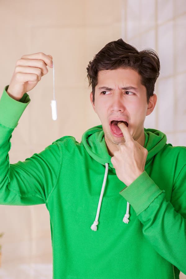 Handsome Man With A Disgusted Face Holding A Menstruation Cotton Tampon Doing A Sign With His