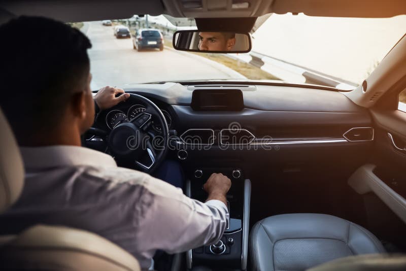 Handsome Man Driving His Modern Car, View from Backseat Stock Photo