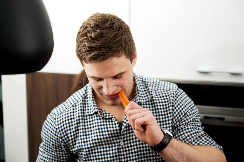 Handsome man eating carrot. stock photography