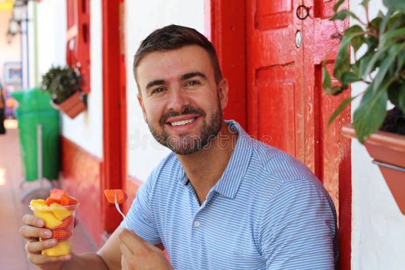Handsome man eating a fruit bowl royalty free stock photography