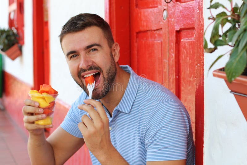 Handsome man eating a fruit bowl royalty free stock photo