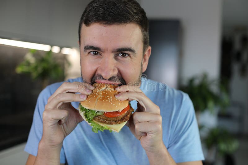 Handsome man eating a hamburger royalty free stock photos
