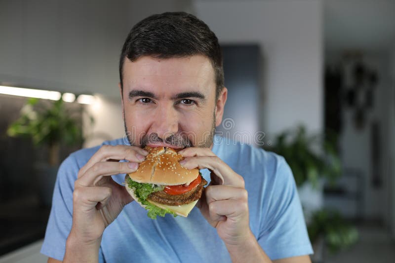 Handsome man eating a hamburger royalty free stock photo