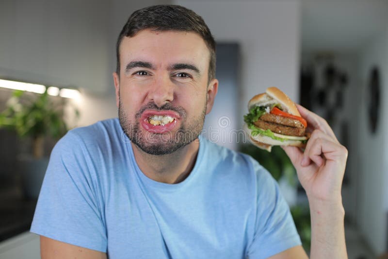 Handsome man eating a hamburger royalty free stock image
