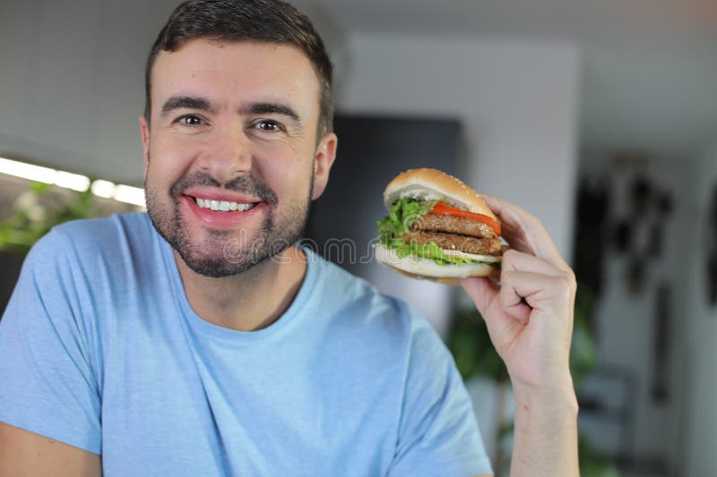 Handsome man eating a hamburger royalty free stock photo
