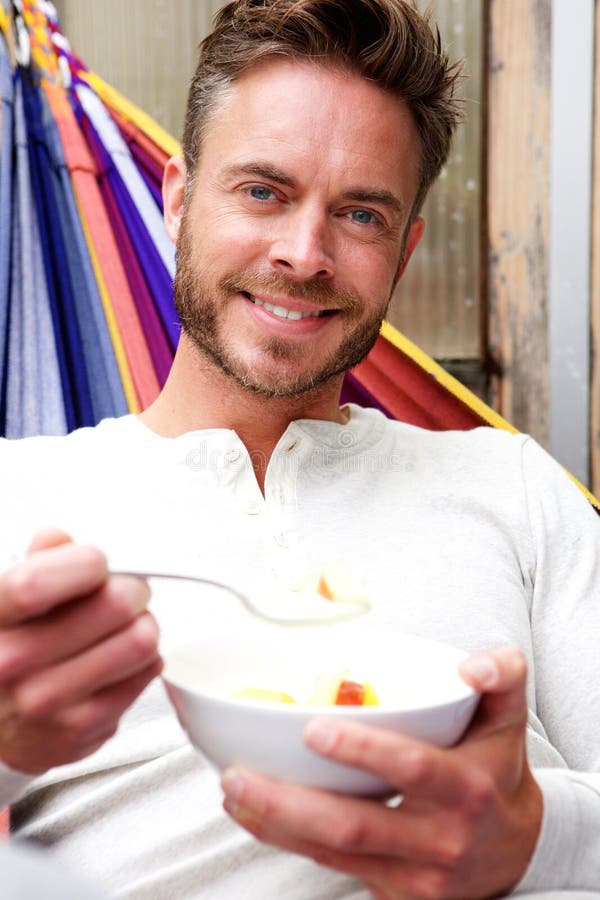 Handsome man eating healthy breakfast in hammock stock photo
