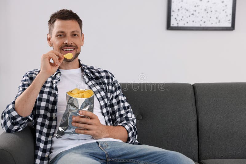 Handsome Man Eating Potato Chips on Sofa at Home Stock Photo Image of