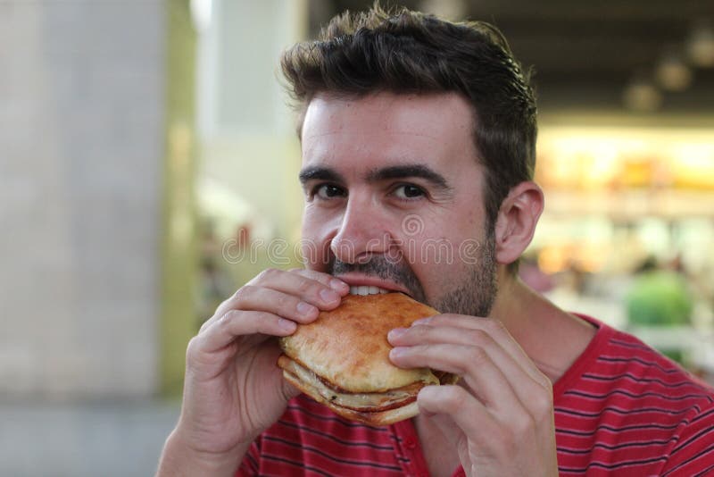 Handsome man eating a sandwich stock photography