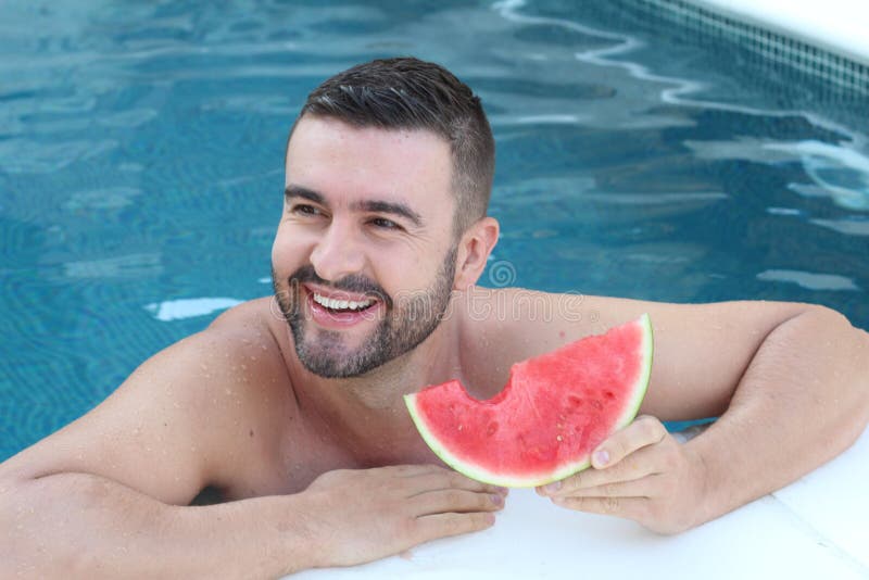 Handsome man eating watermelon in the pool royalty free stock photos